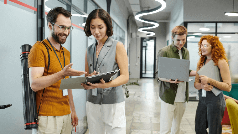 Smiling bearded employee pointing during discussion with diverse colleagues at InHand