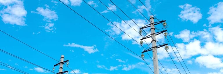 خطوط الكهرباء على خلفية سماء زرقاء غائمة جزئياً تصور البنية التحتية الحديثة للشبكة الذكية لتوزيع الطاقة