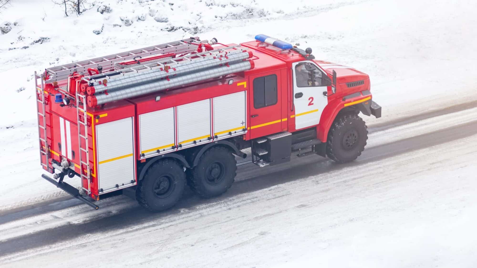Red fire truck driving through snow-covered road for emergency response fleet visibility solutions