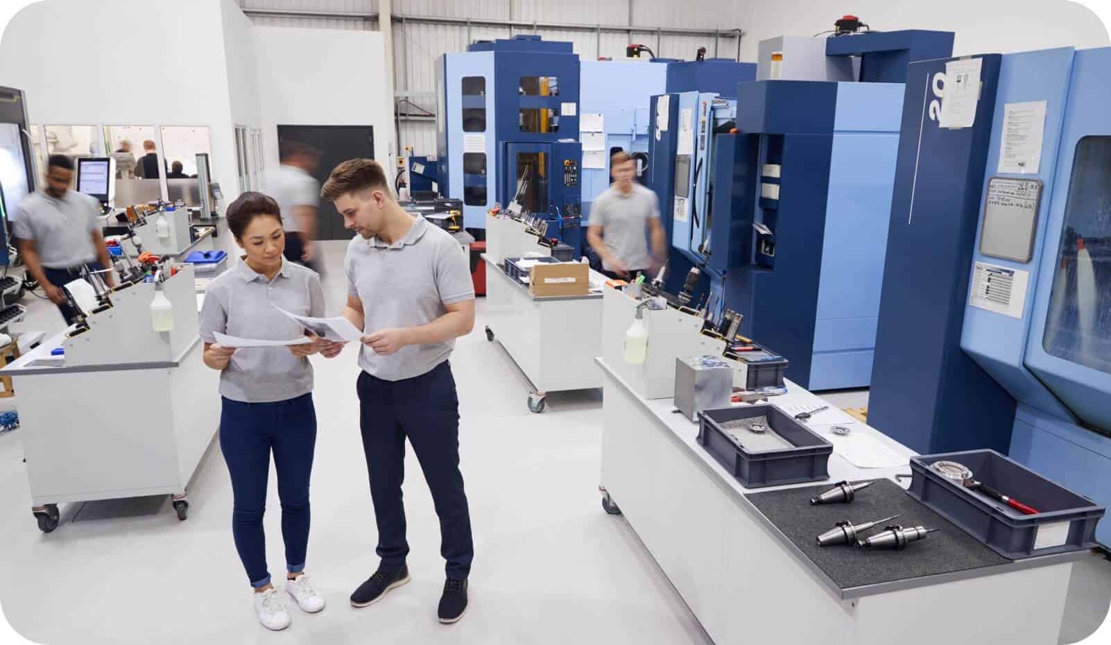 Ingenieure diskutieren die Implementierung des industriellen IoT in einer geschäftigen Fabrikhalle, um Konnektivitätsprobleme zu lösen.