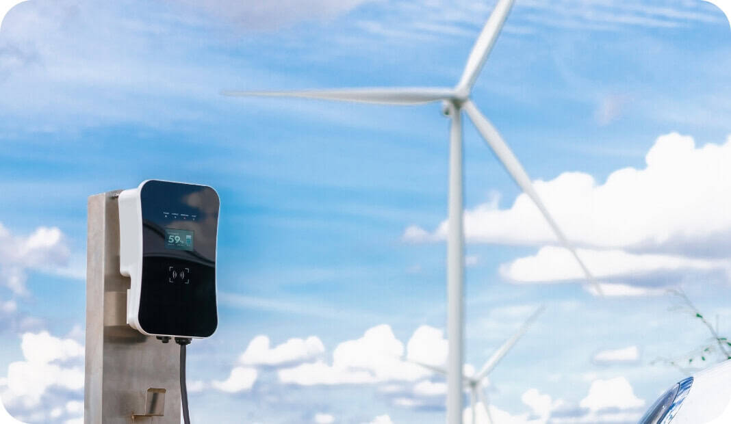 Ladestation für Elektrofahrzeuge am Fuße einer Windkraftanlage, die als Beispiel für Digitalisierungslösungen im Bereich sauberer Energien dient.